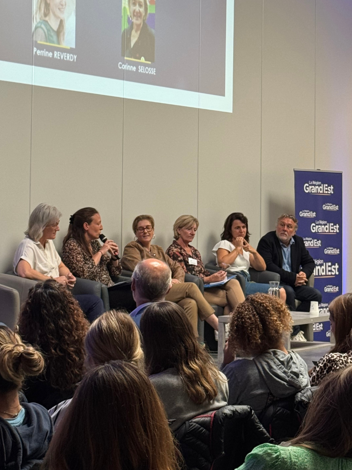 Photo des intervenants de la conférence, sur une estrade, face au public