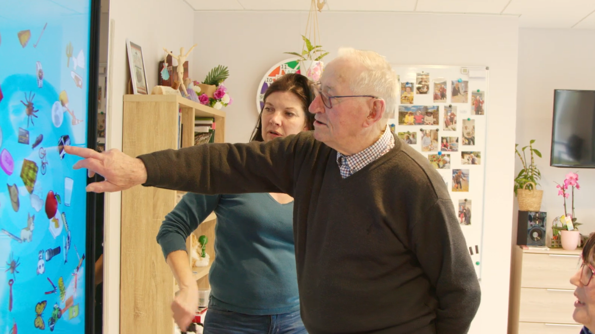 Des personnes âgées utilisent un écran tactile géant 