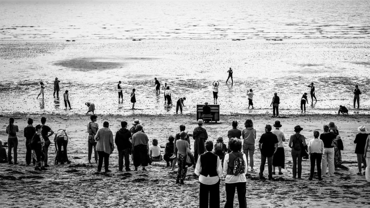 Le Piano de la compagnie "Silence&Songe" dans le sable face à la mer avec une performance d'acteurs autours